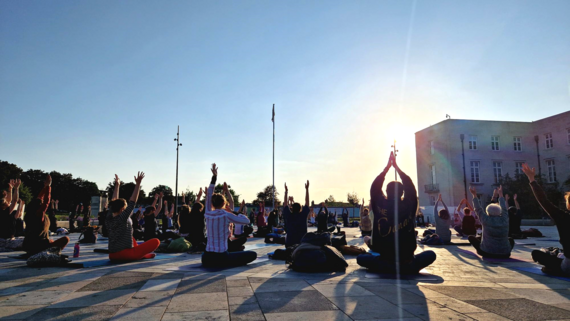 A group of people practise yoga at dusk in Fellowship Square