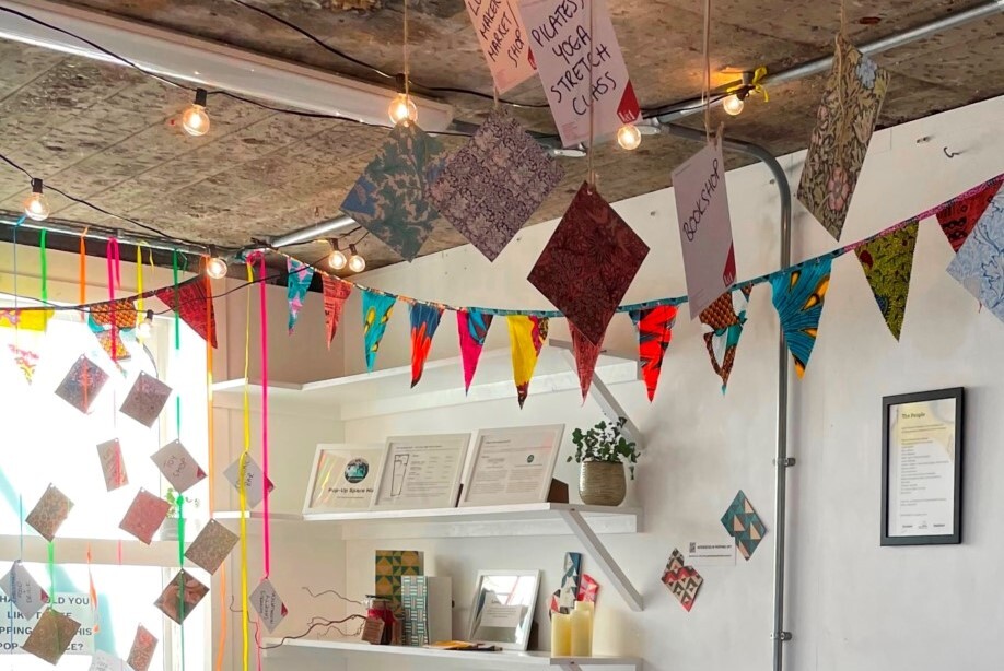 The inside of 1 Church Lane showing bunting and cards hanging from the ceiling advertising plates, yoga and stretch classes