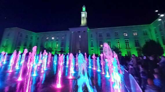 Illuminated Town Hall and fountains in Fellowship Square at night 