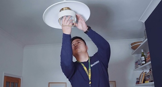 A council worker fits an energy saving lightbulb into a ceiling pendant
