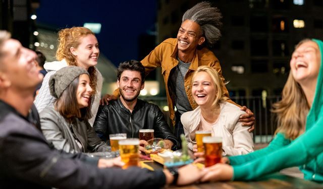 A group of friends smile and laugh over a drink