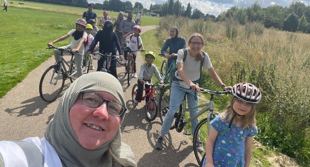 Adults and child cyclists from Joyriders pose on a bike ride on a cycle path, surrounded by grass