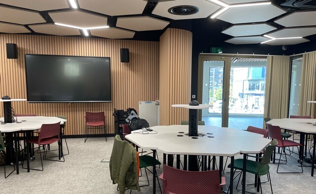 The modern interior of UoP London's Waltham Forest campus showing workstations and a window view