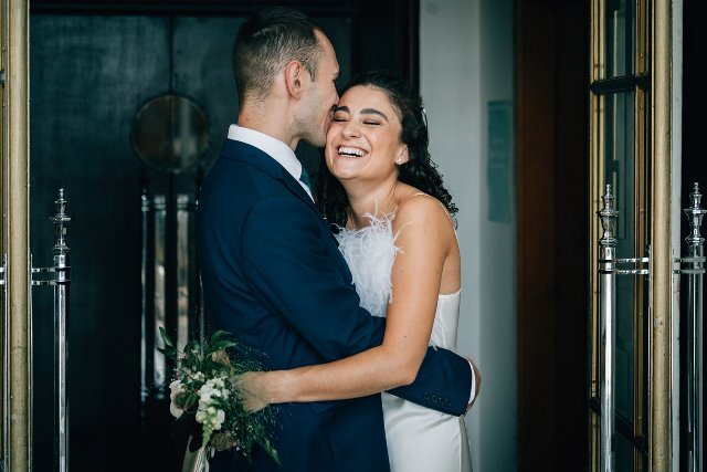 A laughing wedding couple hug