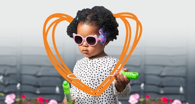 A small child in sunglasses is shown with a heart drawn around their head for Foster Care Fortnight