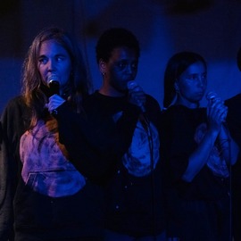 Three women standing in a line holding microphones.