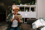 A women uses a tablet computer from her sofa