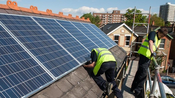 a photograph of some men installing solar panels on a roof