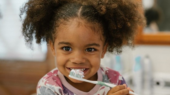 A photo of a young girl brushing her teeth and havin' a smile!