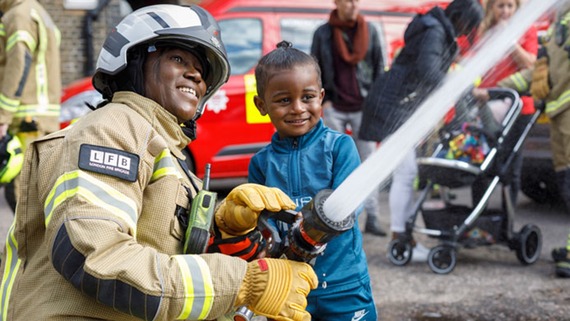 A photo of a firefighter and a child holding a hose