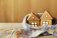 Two wooden toy houses on a table wrapped in a scarf.