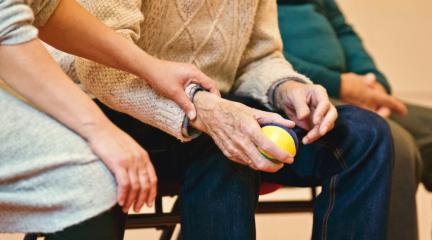 A lady holding the arm of an elderly person