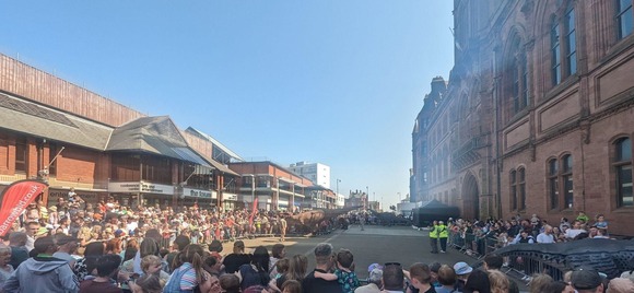 Crowds standing around a rectangular arena watching dinosaurs