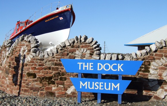 The Dock Museum sign in front of a lifeboat