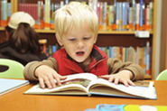 Little boy reading a book in library
