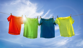 Four colourful tshirts hanging on a washing line in the sun