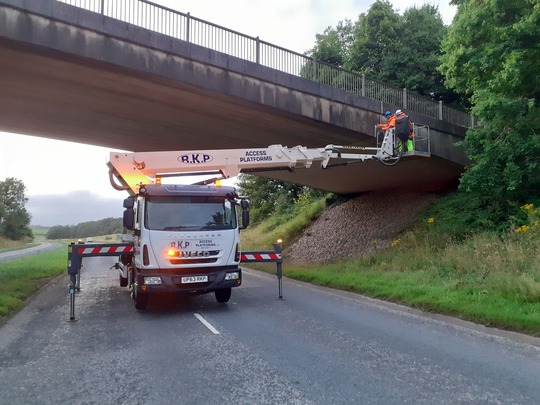 A591 closed with a scissor lift in the middle of the dual carriageway with two officers inspecting the bridges