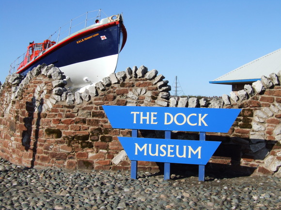 The Dock Museum sign in front of a lifeboat