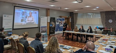 People sitting around a table looking at a presentation.