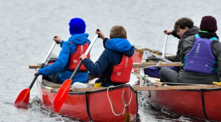 Young people in protective equipment enjoying a paddle boat on a lake