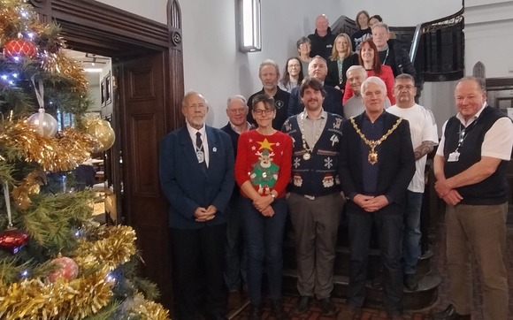 A gathering of people at Kendal Town Hall beside a Christmas tree