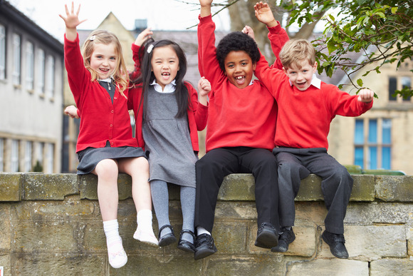 Children sitting on a wall in school uniform