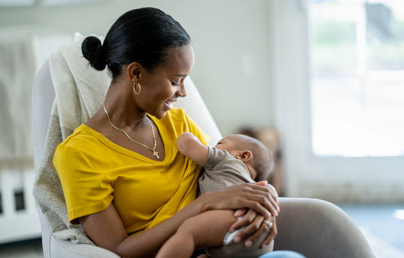 A mother breastfeeding her infant in a chair