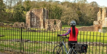 A girl ona bike looking at Furness Abbey.