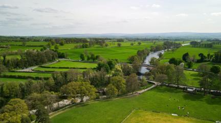 A green landscape with rolling fields with a river running through