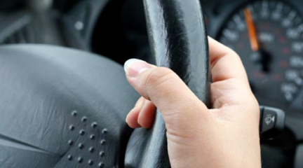 A hand holding the wheel of a car