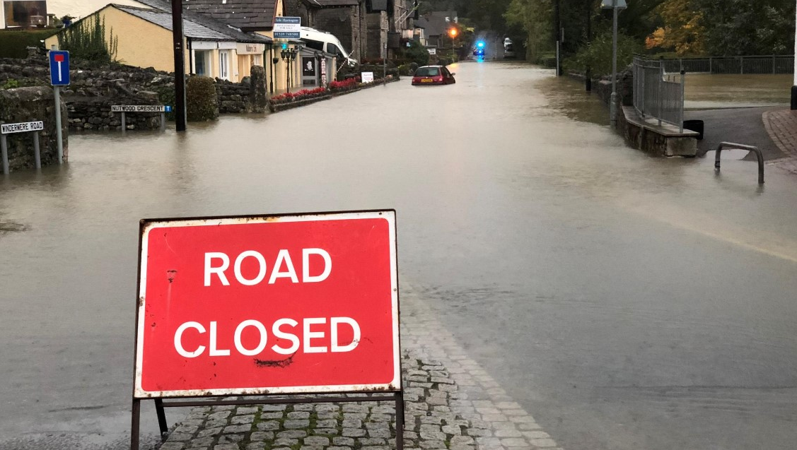 A sign saying 'road closed' in front of a road covered in water