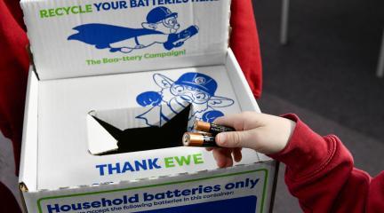 A child putting a used battery in a collection box at school