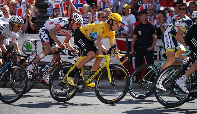 Bradley Wiggins riding a yellow bike and wearing a yellow top and cycling helmet, with spectators in the background