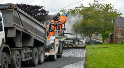 A highways crew undertaking surface dressing on a road