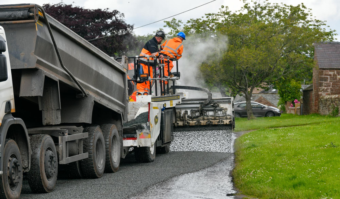 A highways crew undertaking surface dressing on a road.