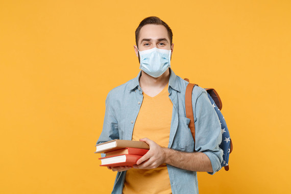 Man with facemask holding books
