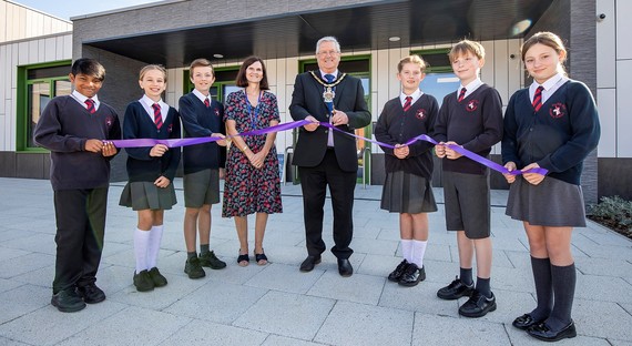 Photo of the Mayor of Wokingham Borough cutting a ribbon outside Farley Hill Primary School on a sunny day with smiling pupils