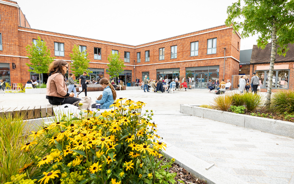 A woman and child sat on the edge of a flowerbed in Wokingham's Peach Place on a sunny day