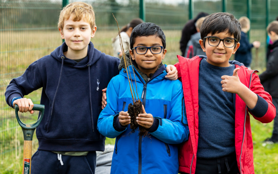 Photo of children holding a sapling and spade