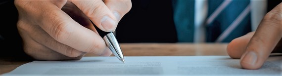 close-up photograph of a male hand signing an official letter