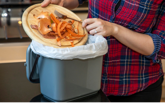 women scraping her food waste into the food waste caddy
