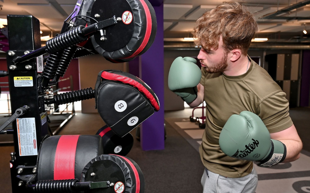 A young man uppercuts a punch bag at our new boxing gym