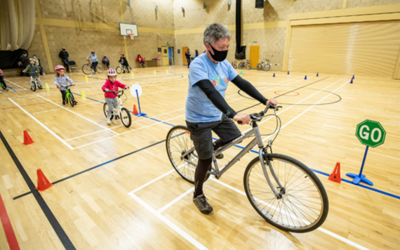 MyJourney Learn to Ride bike class with instructor and children riding round an indoor teaching circuit 