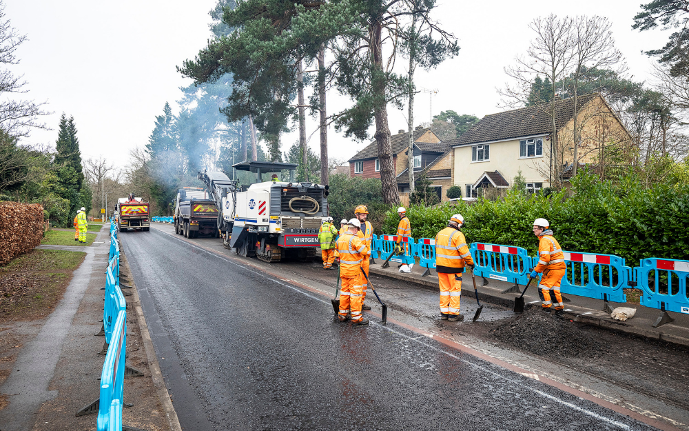 resurfacing teams spread asphalt as part of work to resurface a road