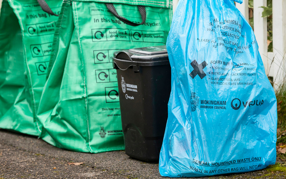 A blue bag, food waste caddy and recycling bag on a kerb
