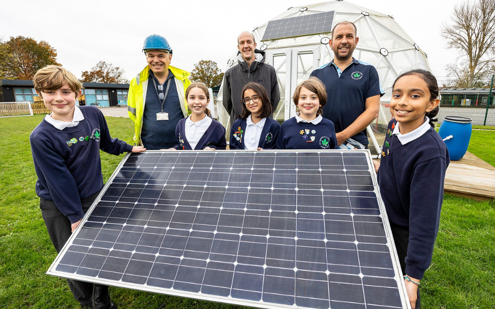 A group of primary school children hold a solar panel and smile