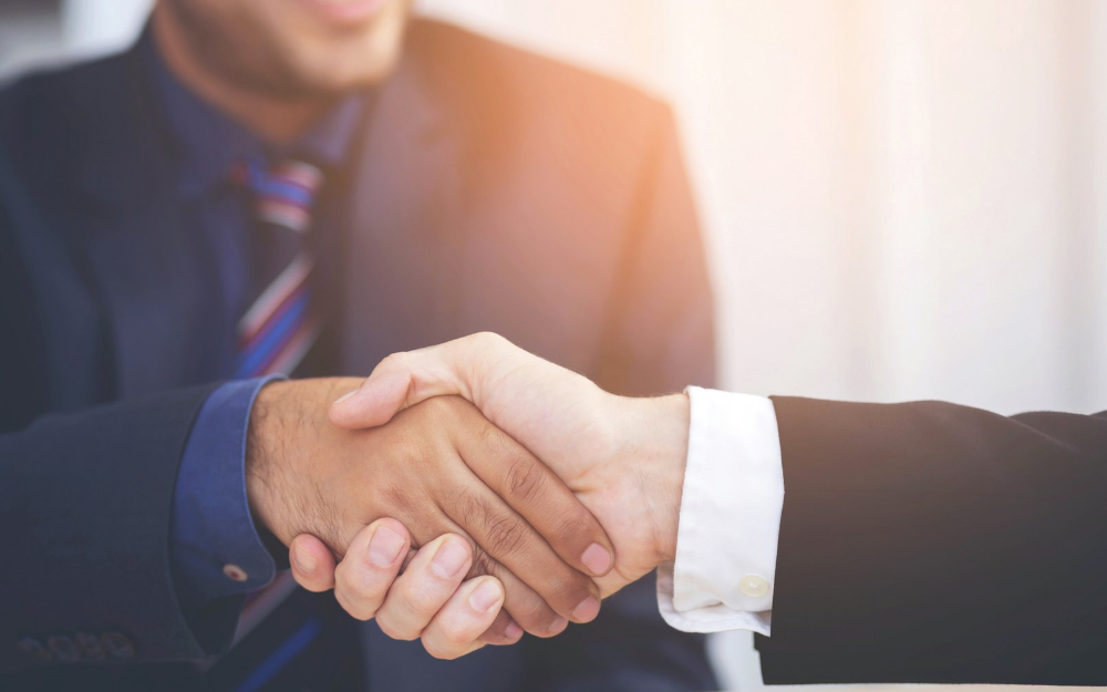 Two men shaking hands in bright sunlight