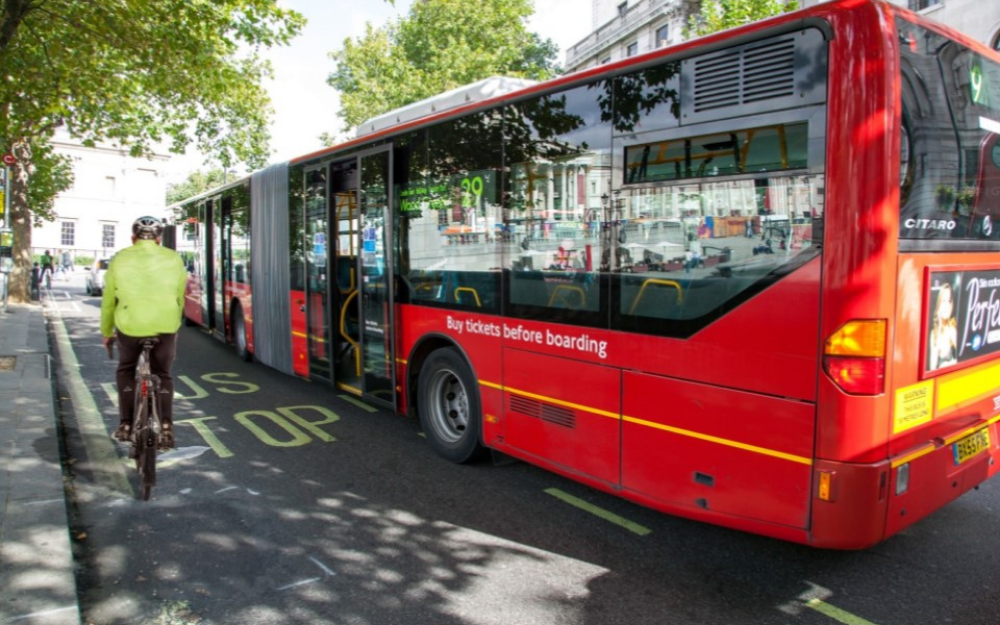 A bus moves around a cyclist on a busy road