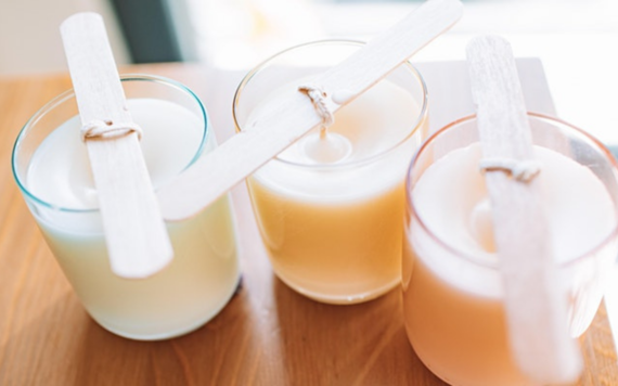 Image of candles being made in three glass jars with wicks being secured waiting for wax to set