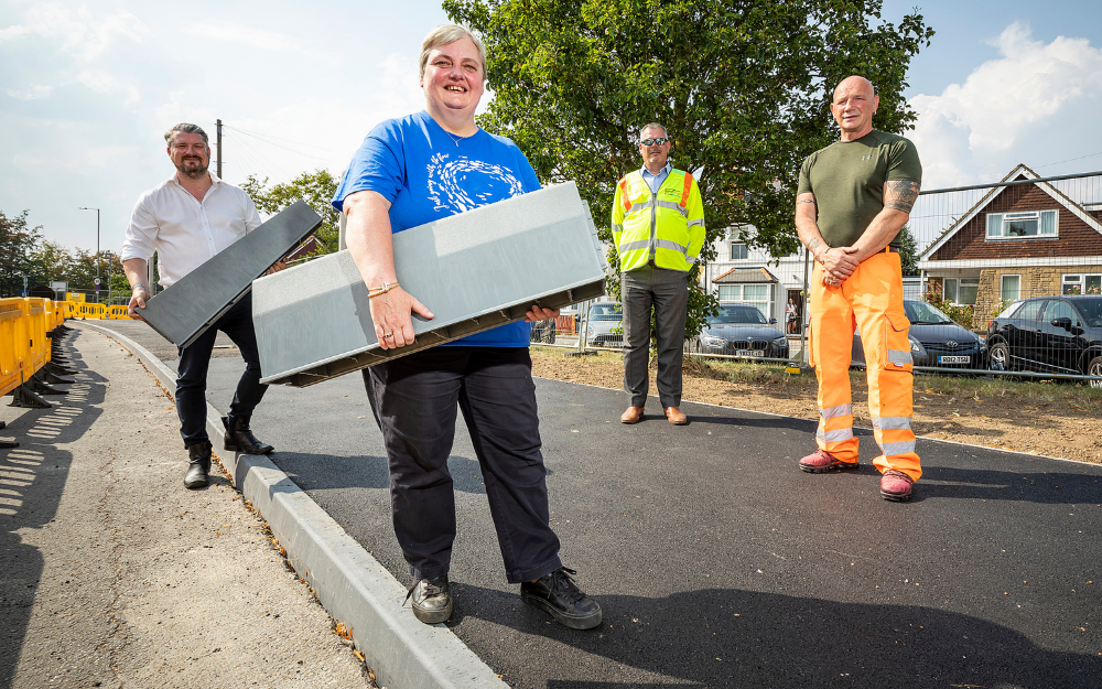 Cllr Pauline Jorgensen holds a plastic kerb next to a newly laid plastic kerbstone in wokingham